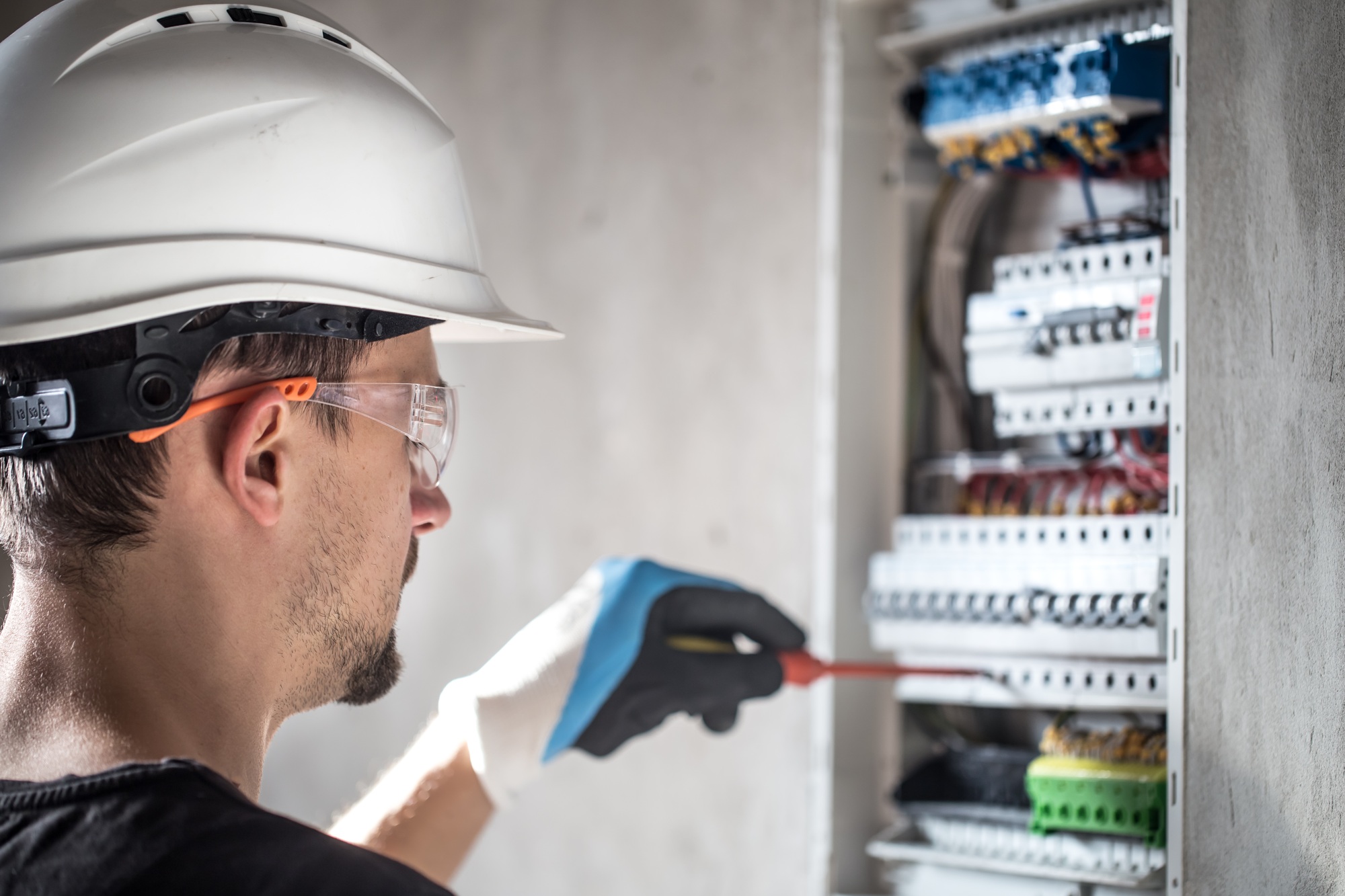 Man, an electrical technician working in a switchboard with fuses.