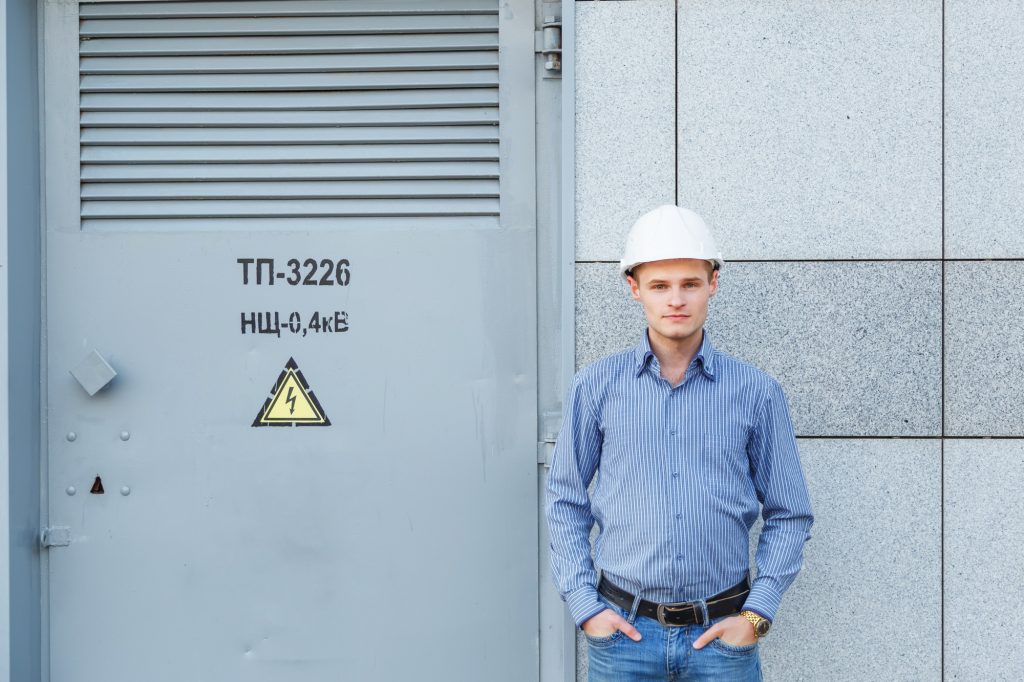Portrait of young engineer at the transformer station